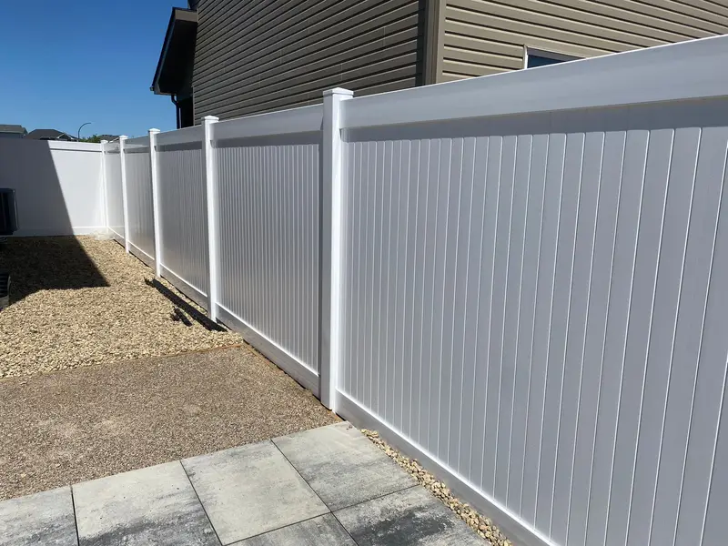 White vinyl privacy fence with flat-cap posts installed along a residential side yard in Saskatoon by Richters Fence Design