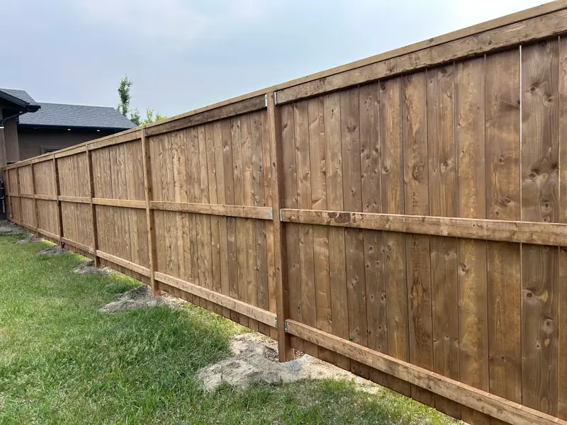 Long stained wood privacy fence running the full length of a backyard in Saskatoon