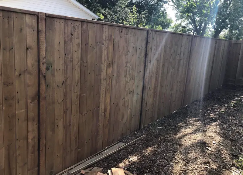 Brown pressure-treated wood privacy fence with vertical boards and a capped top rail in Saskatoon