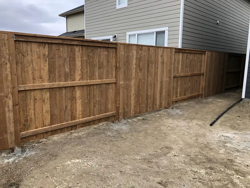 Newly installed stained wood privacy fence dividing two homes in Saskatoon
